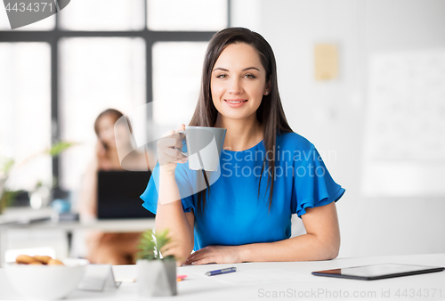 Image of happy businesswoman drinking coffee at office