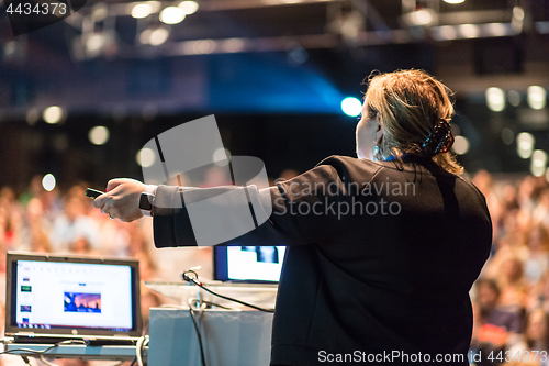 Image of Female public speaker giving talk at Business Event.