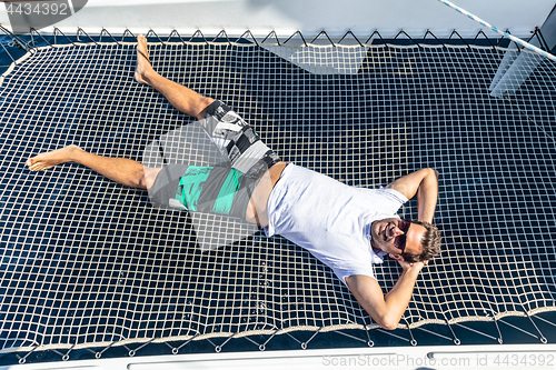 Image of Sporty man relaxing on a luxury catamaran sailing boat.