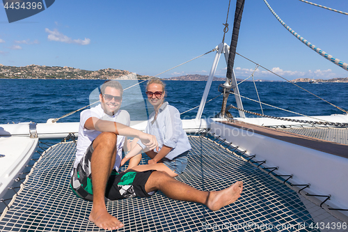 Image of Romantic couple relaxing on a summer sailin cruise, sitting on a luxury catamaran, sailing in Maddalena Archipelago, Sardinia, Italy.