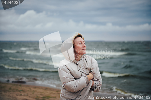 Image of Adult woman in jacket standing near sea