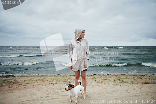 Image of Young woman with dog looking away near sea