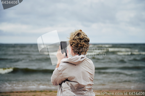 Image of Unrecognizable female taking photo of stormy sea