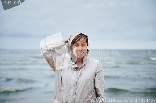 Image of Young woman in jacket near sea