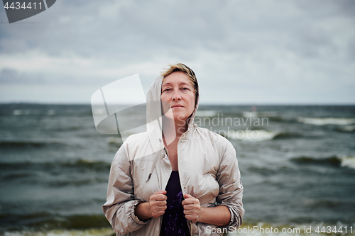 Image of Adult woman in jacket standing near sea