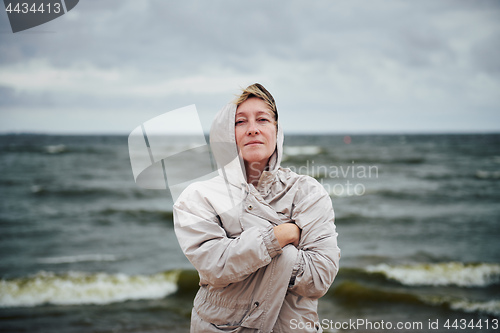 Image of Adult woman in jacket standing near sea