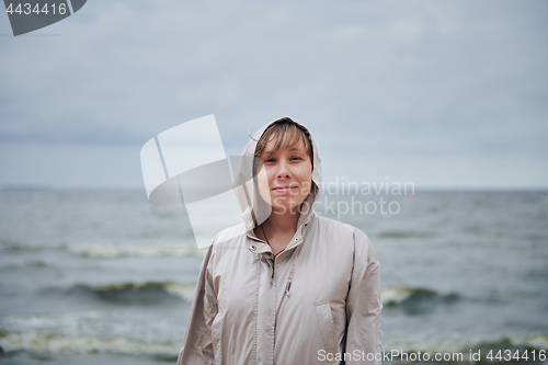 Image of Smiling young woman standing near sea