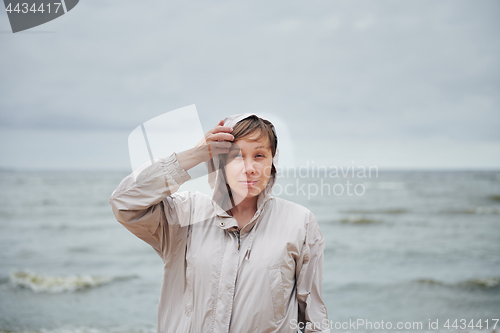 Image of Young woman in jacket near sea