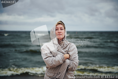 Image of Adult woman in jacket standing near sea