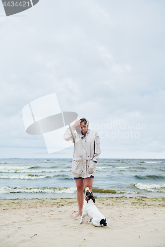 Image of Woman in jacket looking at dog near sea