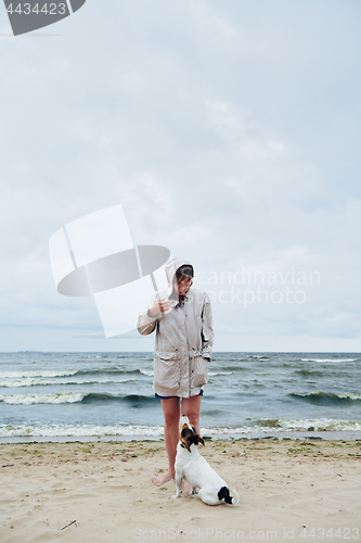 Image of Woman in jacket looking at dog near sea