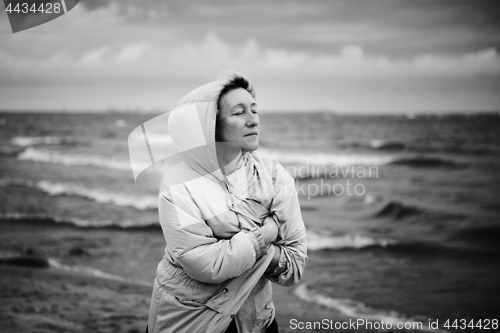 Image of Adult woman wrapping in jacket near sea