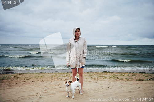 Image of Woman in jacket looking at dog near sea