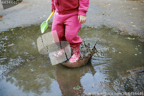 Image of Child jumps in a dirty puddle