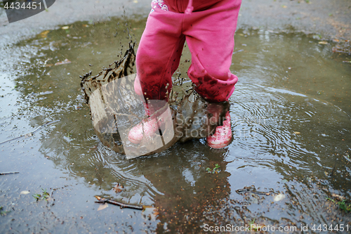 Image of Child jumps in a dirty puddle