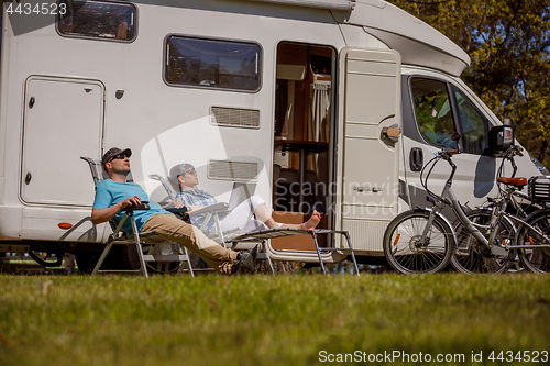 Image of Woman with a man resting near motorhomes in nature. Family vacat