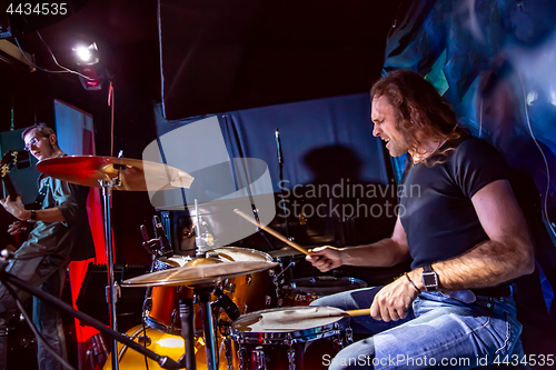 Image of Drummer playing on drum set on stage.