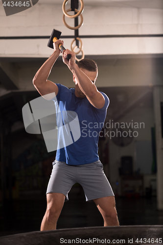 Image of man workout with hammer and tractor tire