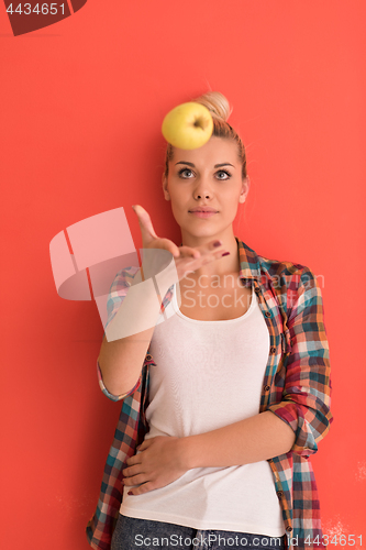 Image of woman over color background plays with apple