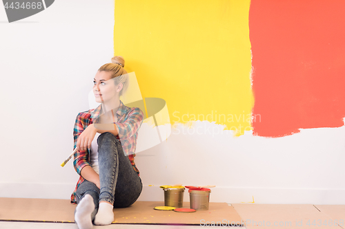 Image of young female painter sitting on floor