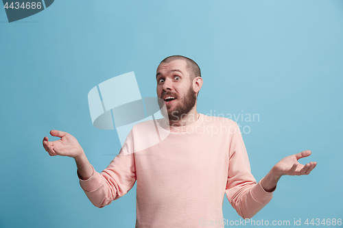 Image of The young attractive man looking suprised isolated on blue