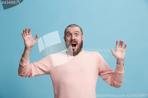 Image of The young attractive man looking suprised isolated on blue