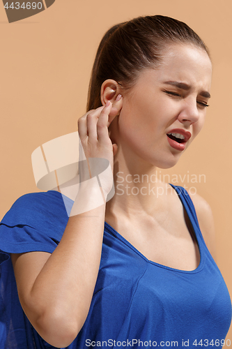 Image of The Ear ache. The sad woman with headache or pain on a blue studio background.