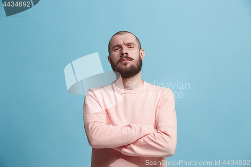 Image of The serious businessman standing and looking at camera against blue background.