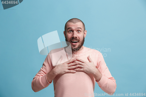 Image of The young attractive man looking suprised isolated on blue