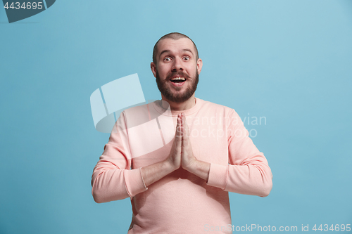 Image of The young attractive man looking suprised isolated on blue