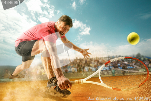 Image of The one jumping player, caucasian fit man, playing tennis on the earthen court with spectators