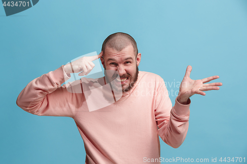 Image of Beautiful male half-length portrait isolated on blue studio backgroud. The young emotional surprised man
