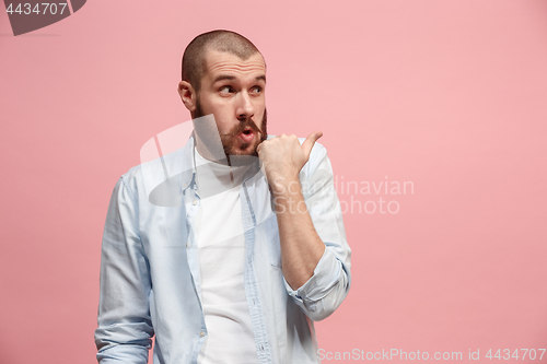 Image of The young man whispering a secret behind her hand over pink background