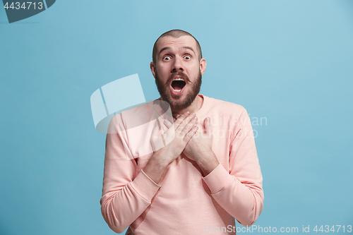 Image of The young attractive man looking suprised isolated on blue