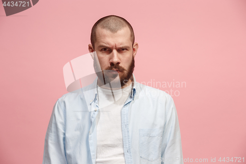 Image of The serious businessman standing and looking at camera against pink background.