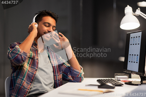 Image of man with headphones listening to music at office