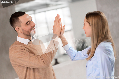 Image of man and woman making high five at office