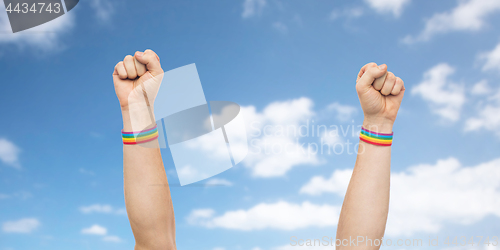 Image of hands with gay pride rainbow wristbands shows fist