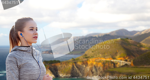 Image of woman with earphones running over big sur coast