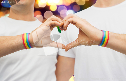 Image of gay couple with rainbow wristbands and hand heart