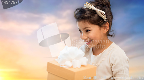 Image of happy girl with gift box over evening sky