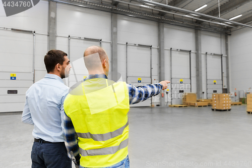 Image of businessman showing warehouse to worker