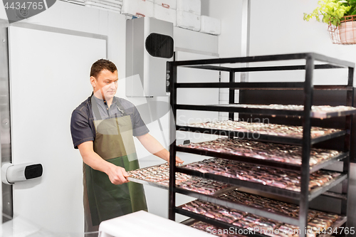 Image of man with smoking tray at fish shop or smokehouse