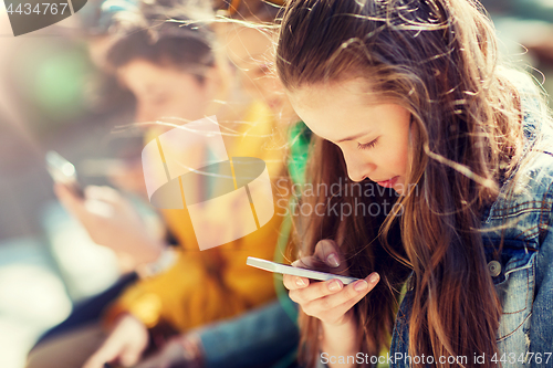 Image of happy teenage friends with smartphones outdoors