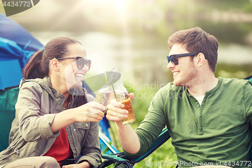 Image of happy couple clinking drinks at campsite tent