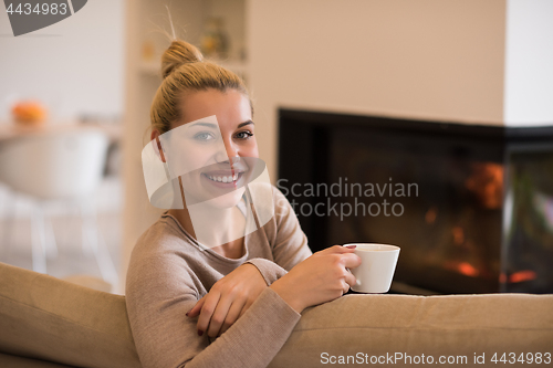 Image of woman with a mug near a fireplace