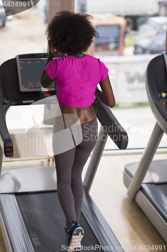 Image of afro american woman running on a treadmill