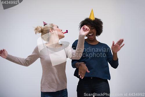 Image of smiling women in party caps blowing to whistles