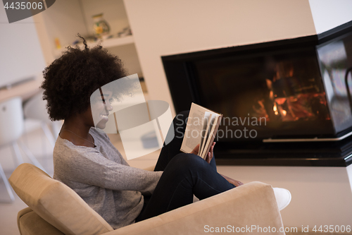 Image of black woman at home reading book