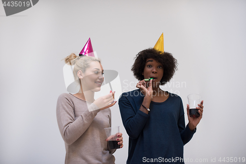 Image of smiling women in party caps blowing to whistles